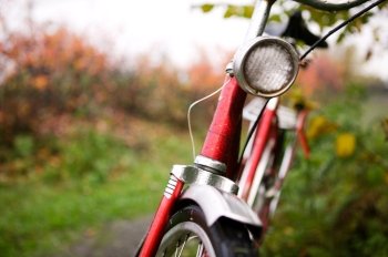 An old red bike detail with a shallow depth of field on a rainy autumn day.