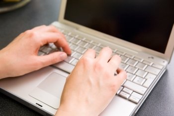 A pair of female hand using a laptop computer.  Shallow depth of field with the focus on the hands.