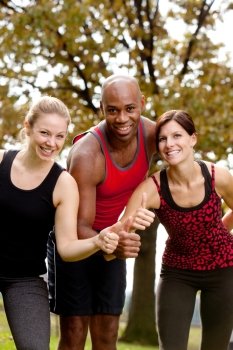 A group of people exercising in the park, giving a thumbs up to the camera