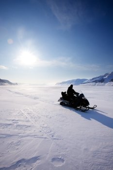 A snowmobile on frozen ice on a barren winter landscape