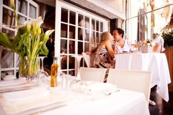 A romatic couple kissing in an outdoor restaurant