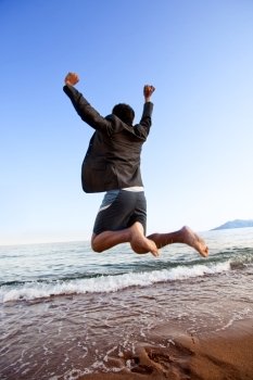 A happy business man jumping by the ocean - happy successful concept