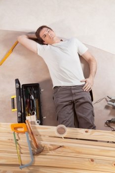 Thoughtful man on the floor with carpentry tools around
