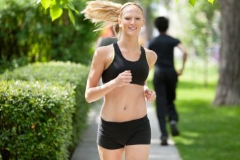 Beautiful woman running in park with people in the background