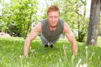 Caucasian man doing a push up in park against blur background