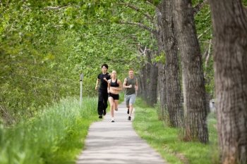 Young people running on walkway by trees