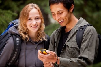 A man and woman looking at a gps in the forest