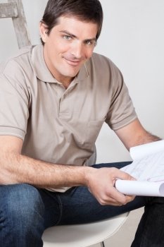 Portrait of happy mature man holding a blueprint plan in his hand