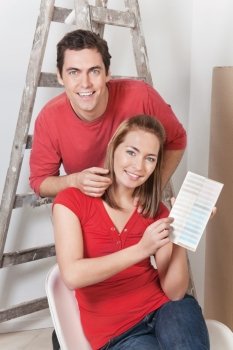 Young happy couple pointing at color card