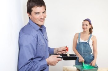 Portrait of young husband mixing paint while wife watching