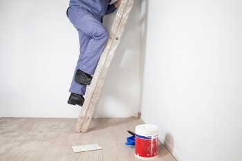 Low section of man’s legs climbing wooden ladder