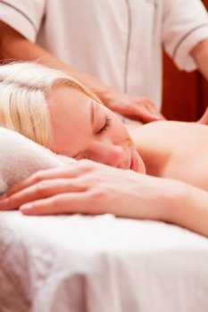 A relaxed woman receiving a back massage in a spa