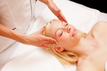 Portrait of a woman in a spa receiving a scalp massage