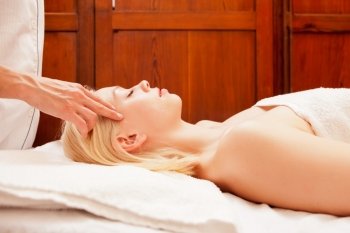 A beautiful blonde woman receiving a head and scalp massage in a spa