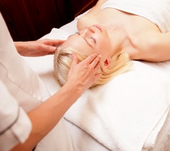 A tranquil woman receiving a head massage at a spa