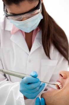 Female dentist examining man’s teeth in dental office