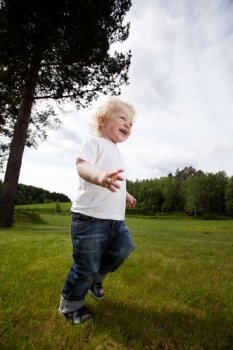 A young toddler boy running in an open grass area, excited and free