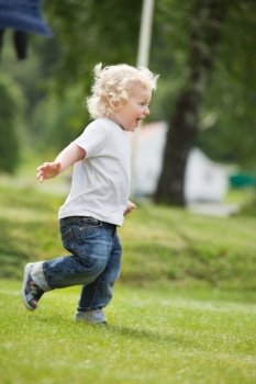 Full length of happy little boy running in garden with mouth open