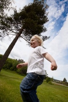 A young toddler boy running outside in a rural farm setting