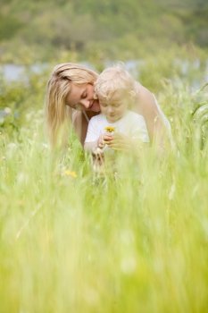 A happy cheeful mother and son in green picturesque meadow