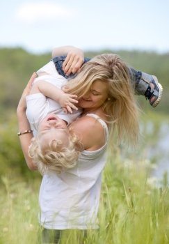 A mother and son playing, laughing and having fun in a prairie meadow