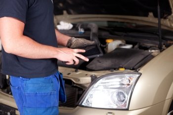 Detail of a mechanic with a digital tablet, car in background