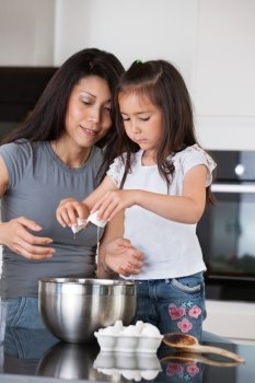Woman teaching child to prepare dough with healthy ingredients
