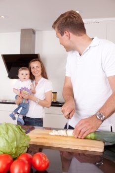 A family at home in the kitchen making a meal together, shallow depth of field, critical focus on father