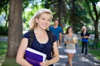 Portrait of happy young girl smiling while her classmates walking in background