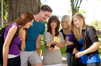 Group of students outdoors looking at a humorous image on a cell phone