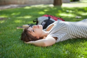 Young college student lying on grass at campus lawn