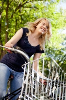 Attractive young female riding a bike through green nature