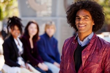 Group of four people of different ethnicities with one man as focus of image. Horizontally framed shot.