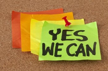 yes we can - motivational slogan on a stack of sticky notes posted on cork bulletin board