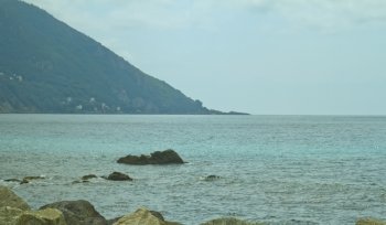Calm sea scene with rocks and far coastline