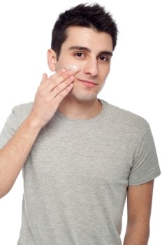handsome young man applying cream lotion on face (isolated on white background)