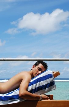 beautiful photo of a man resting/sunbathing at a Maldives resort (ocean/cloud background)