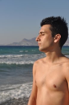 handsome young man getting suntan at Kos beach in Greece (blue sky)