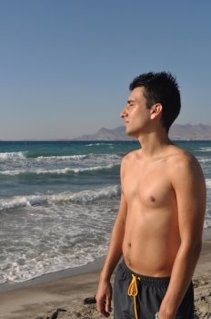 handsome young man getting suntan at Kos beach in Greece (blue sky)