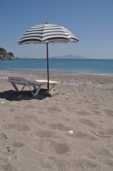gorgeous beach scene with greek umbrella and chair at Kefalos beach (Kos), Greece