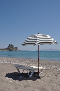 gorgeous beach scene with greek umbrella and chair at Kefalos beach (Kos), Greece