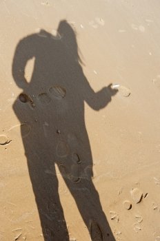 Shadow of woman with feather in her hand in beach at the Baltic sea