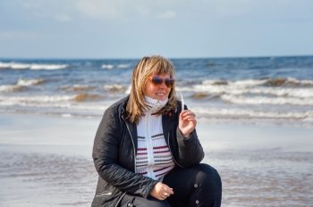 Mature chubby woman relaxing at the Baltic sea in autumn day.