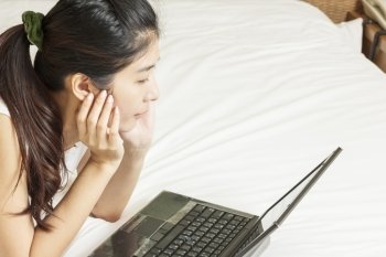 happy young asian woman working with laptop in bedroom