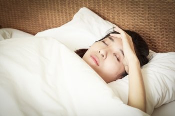 woman with headache lying on bed