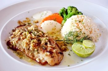 roasted fish served with fried rice  fresh lemon and vegetable