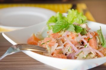 close up of spicy salmon salad with  mixed  vegetable with silver fork. spicy salmon salad
