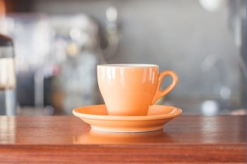 Orange coffee cup in coffee shop, stock photo