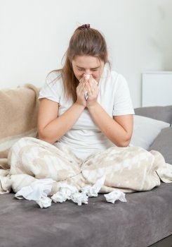 Brunette woman in blanket blowing nose
