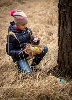 Little girl having Easter egg hunt at forest